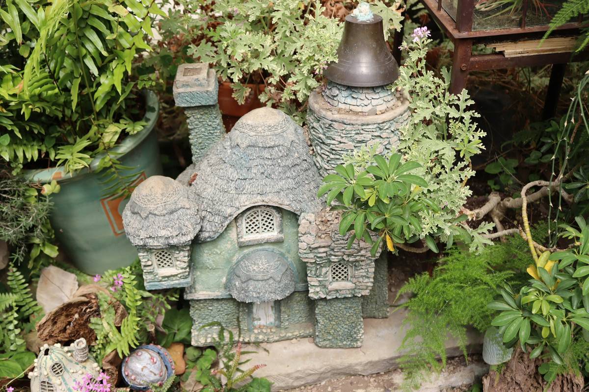 unique garden ornaments uk displayed among flowering shrubs and stone pathways